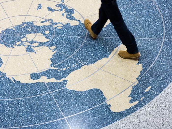 legs walking across a world map on the floor