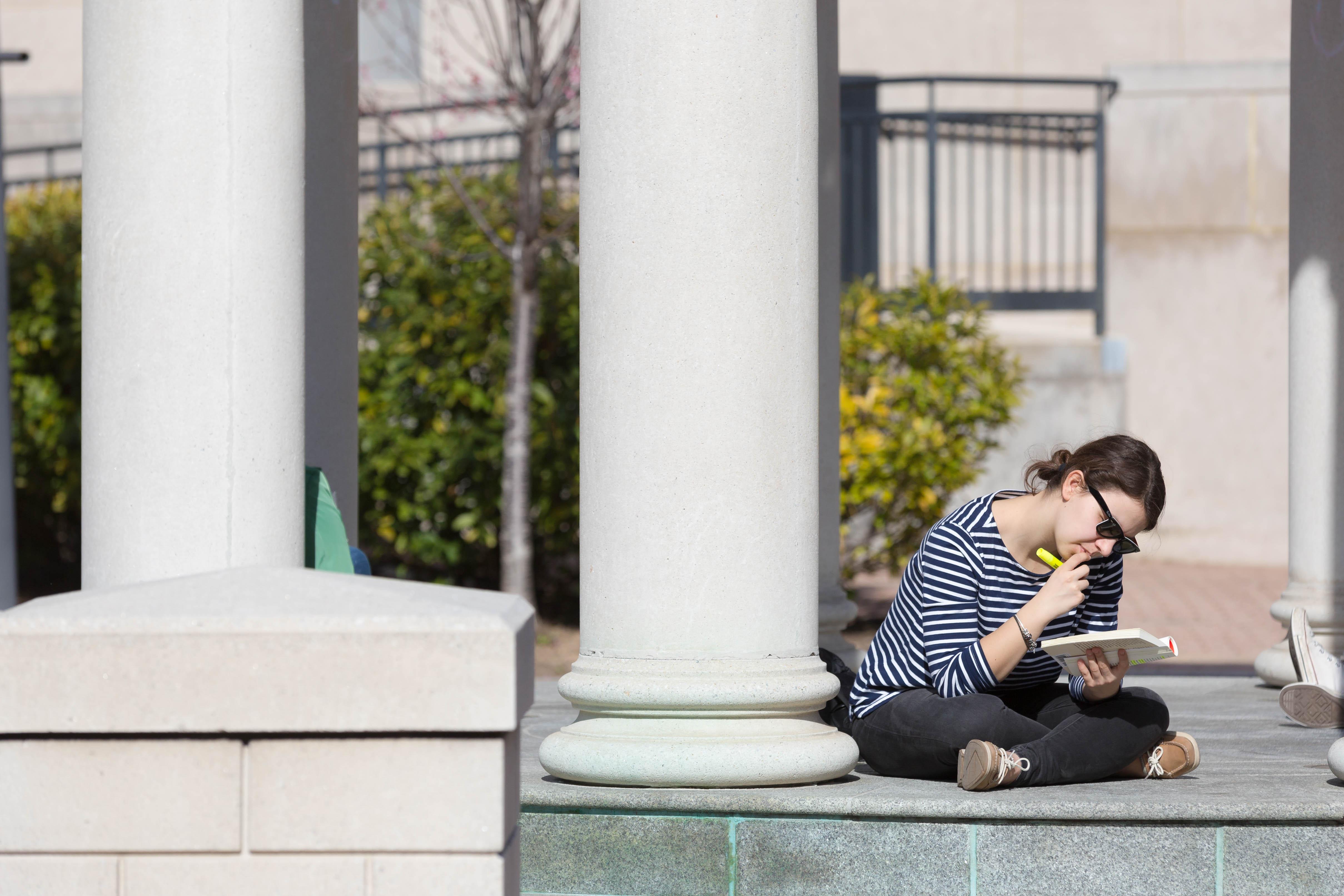 Student studying while sitting outside  on campus